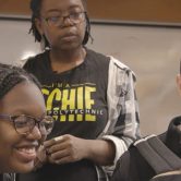 Three students looking at laptop together