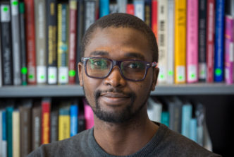 Photograph of Abdullahi Tsanni in front of shelves of books