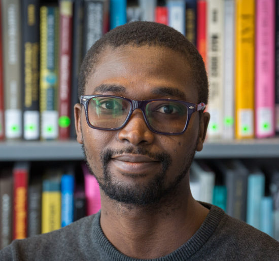 Photograph of Abdullahi Tsanni in front of shelves of books